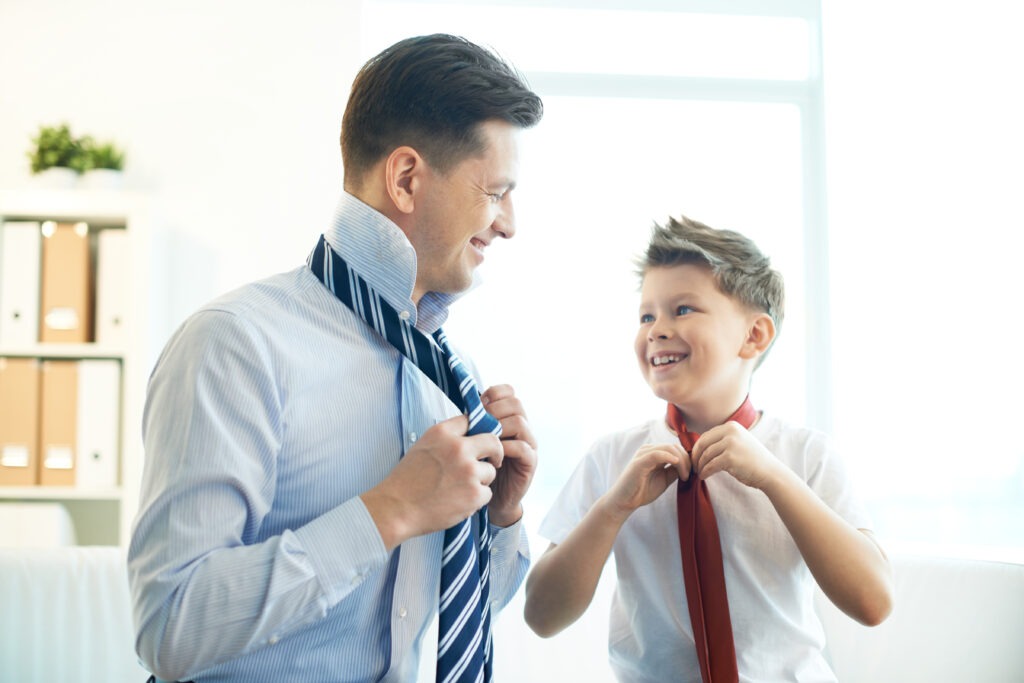 Photo of happy boy and his father tying neckties